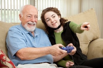 Teen girl shows her grandfather how to play video games.