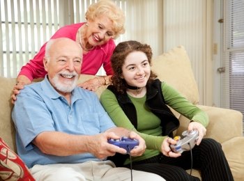 Senior couple has fun playing video games with their teenage granddaughter.