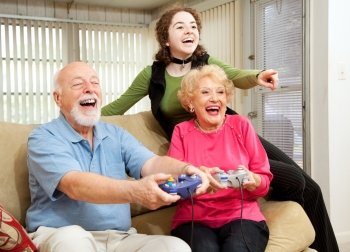 Grandparents and teen girl having fun playing video games.