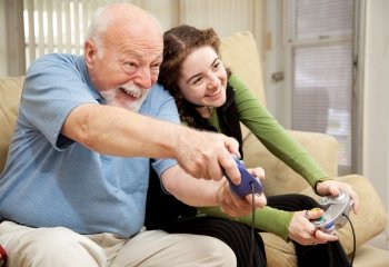 Grandfather enjoys playing video games with his teenage granddaughter.