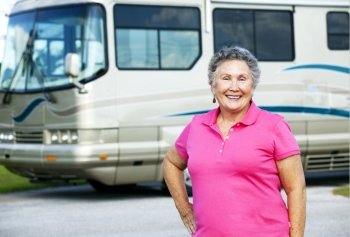 Portrait of a pretty senior woman in front of her luxury motor home.  