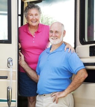 Senior couple posing in the doorway of their luxury motor home.  
