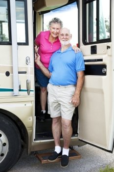 Senior couple posing in the door of their luxury RV.  