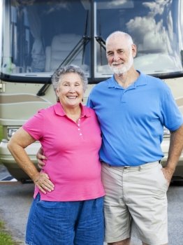 Portrait of healthy retired couple in front of their motor home.