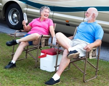 Senior campers sitting in folding chairs outside their motor home.  