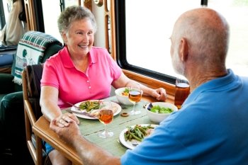 Senior couple holding hands about to eat a healthy meal in their motor home.