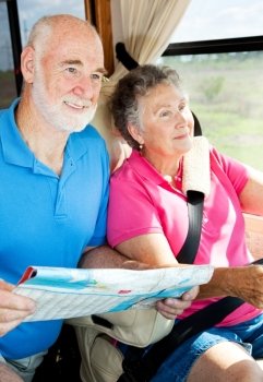Senior couple reading a map and traveling in their motor home.  