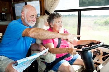 Senior couple traveling in their motor home.  The husband is giving directions to the wife.  