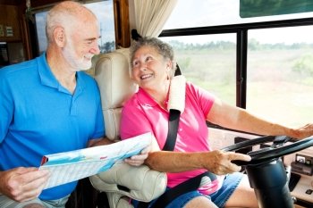 Senior couple riding in their motor home consult a map.  