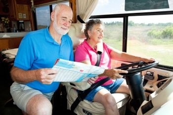 Senior couple on the road in their RV.  The wife is driving while the husband reads the map.