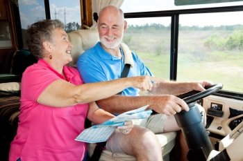Senior couple on vacation in their motor home.  The wife is reading the map for the husband.