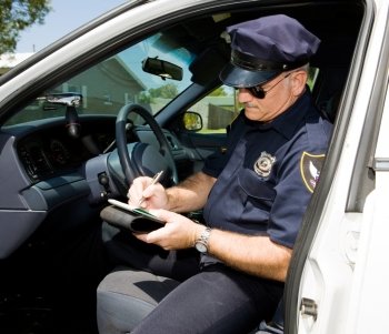 Police officer in his squad car, filling out a citation.  
