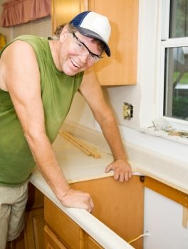 Friendly contractor leans on a formica counter in a kitchen he is remodeling.