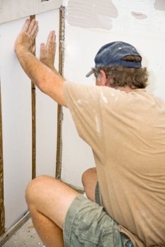 Contractor installing styrofoam insulation in a section of wall he is replacing. 
Authentic and accurate content depiction.  