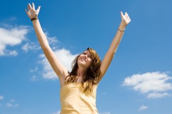 Beautiful teen girl raising her arms and looking to heaven in praise.  