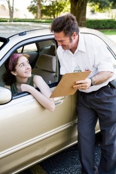 Driving instructor showing a teen driver the results of her test.  