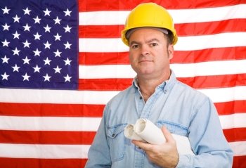 Construction worker with blueprints in front of an American flag.  Photographed in front of the flag, not a composite image.  