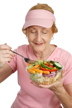 A woman dressed for Breast Cancer Awareness eating a delicious, healthy salad.  White background.