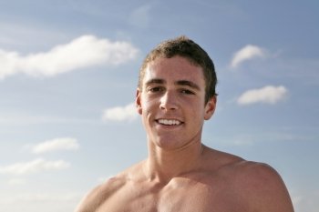 A handsome young man, shirtless against a blue sky.  