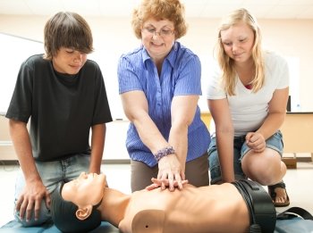 Teacher demonstrates CPR life saving techniques for her teenage students.  