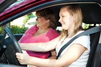 Teenage daughter gets a driving lesson from her mother or an instructor.  