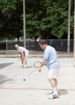 Father and adult son playing racquetball outdoors.  
