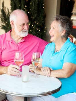 Senior couple enjoying a glass of wine and conversation at an outdoor cafe.  