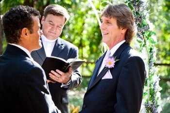 Handsome groom looks lovingly into his partner’s eyes during their wedding ceremony.  