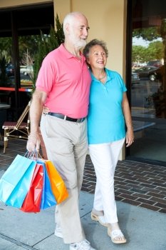 Happy senior couple walking at the mall with shopping bags.  