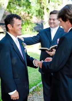 Groom slips a ring on his husband’s finger during a gay marriage ceremony.  