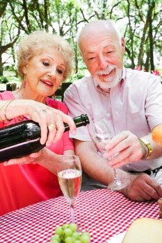 Senior couple on a romantic picnic.  The wife is pouring champagne.  