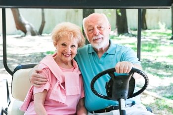 senior couple riding around in a golf cart.  