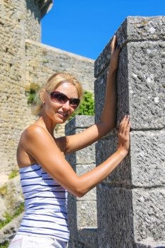Attractive girl in sunglasses near the fortress wall