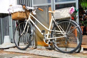 Bicycle with wicker basket stands near wall