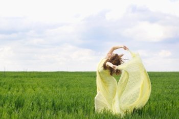 Nice young woman dancing in a green field