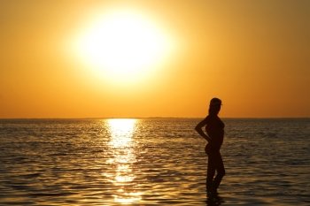 Silhouette of the young woman on a sea bay on a sunset