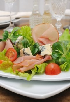 Appetizer with ham and blue cheese in lettuce leaves with corn salad