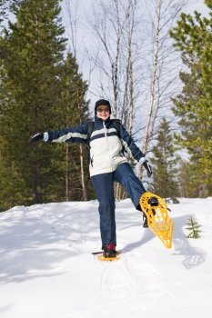 Woman snowshoeing in the forest and smiling.