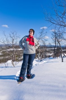 Woman snowshoeing in the hill and enjoying the view.