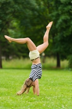 Young girl doing headstand at the park with narrow depth of field