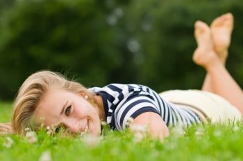 Young smiling girl lying on the grass with very narrow depth of field and focus on the eyes