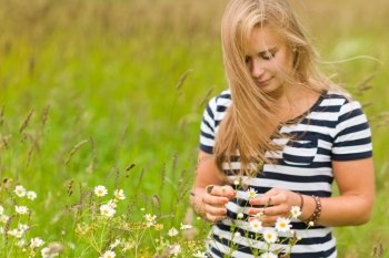 Young beauty girl on the meadow with very narrow depth of field and focus on the hands and flowers