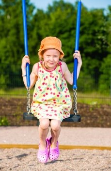 Smiling young girl on the swing, sunny day