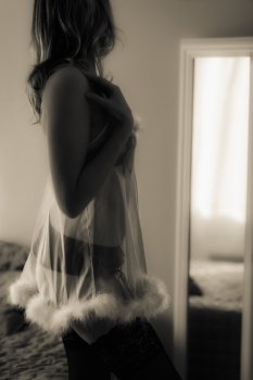 Woman in nightdress posing front of mirror, tinted black and white image, vertical format