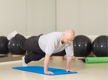 Mature man takes care of his health, he exercise pilates and stretching in a gym