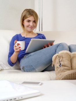 Photo of a happy young teenage female using a computer tablet at home.
