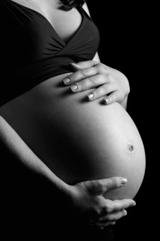 Photo of a pregnant female with her hands on her belly done in black and white