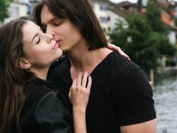 Photo of a young woman and man in love and kissing outdoors.
