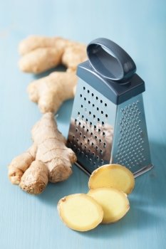 fresh ginger and grater over blue