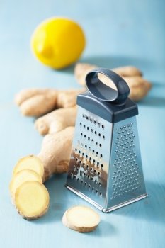 fresh ginger root and grater over blue 